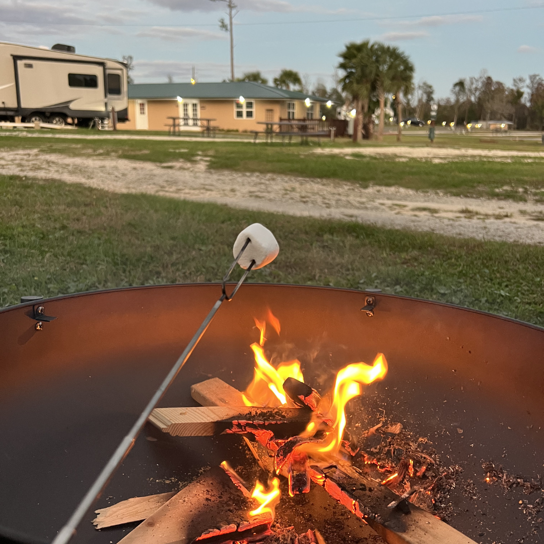 Roasting marshmallows over a fire pit at Florida Caverns RV Resort at dusk